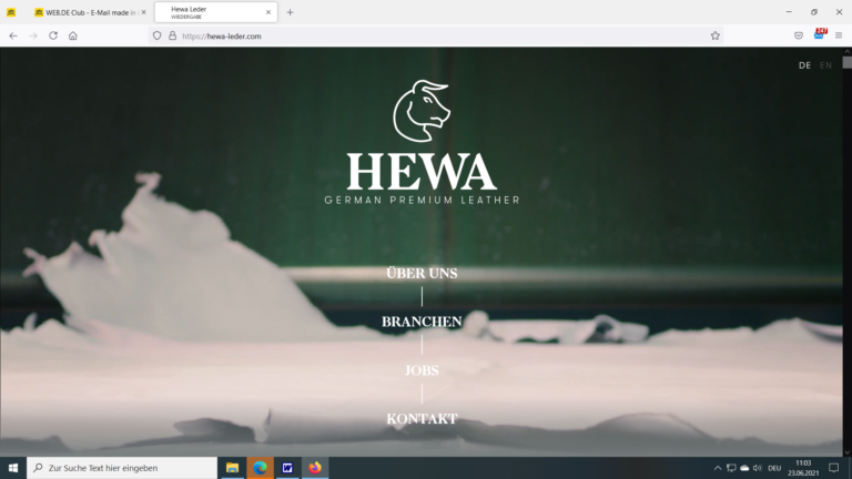 HEWA Leder Logo und Startseite mit Navigationsmenu auf bergigem Hintergrund
