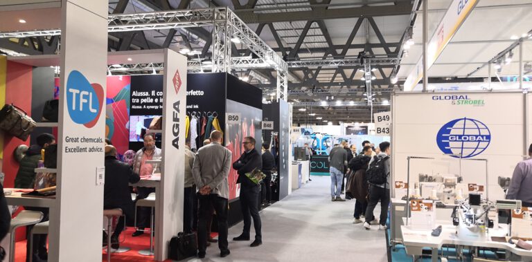 Messestand auf Branchenmesse mit Besuchern, Ausstellungsflächen verschiedener Unternehmen und Industrieausrüstung in Messehalle.
