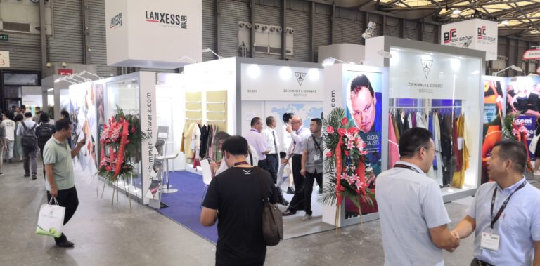 Messestand auf einer Fachmesse in einer Industriehalle mit Besuchern und ausgestellten Produkten der Lederbranche.