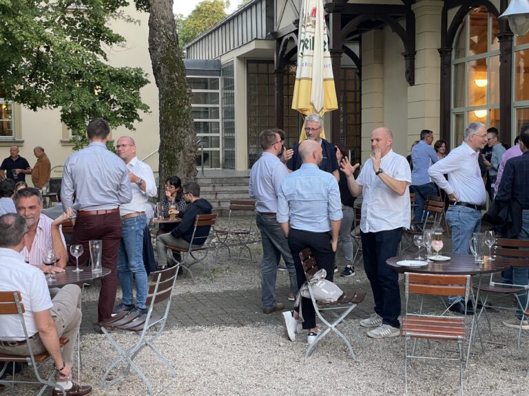 Besucher der Freiberger Ledertage stehen und sitzen in entspannter Atmosphäre auf einem Innenhofplatz vor einem historischen Gebäude mit Terrasse.